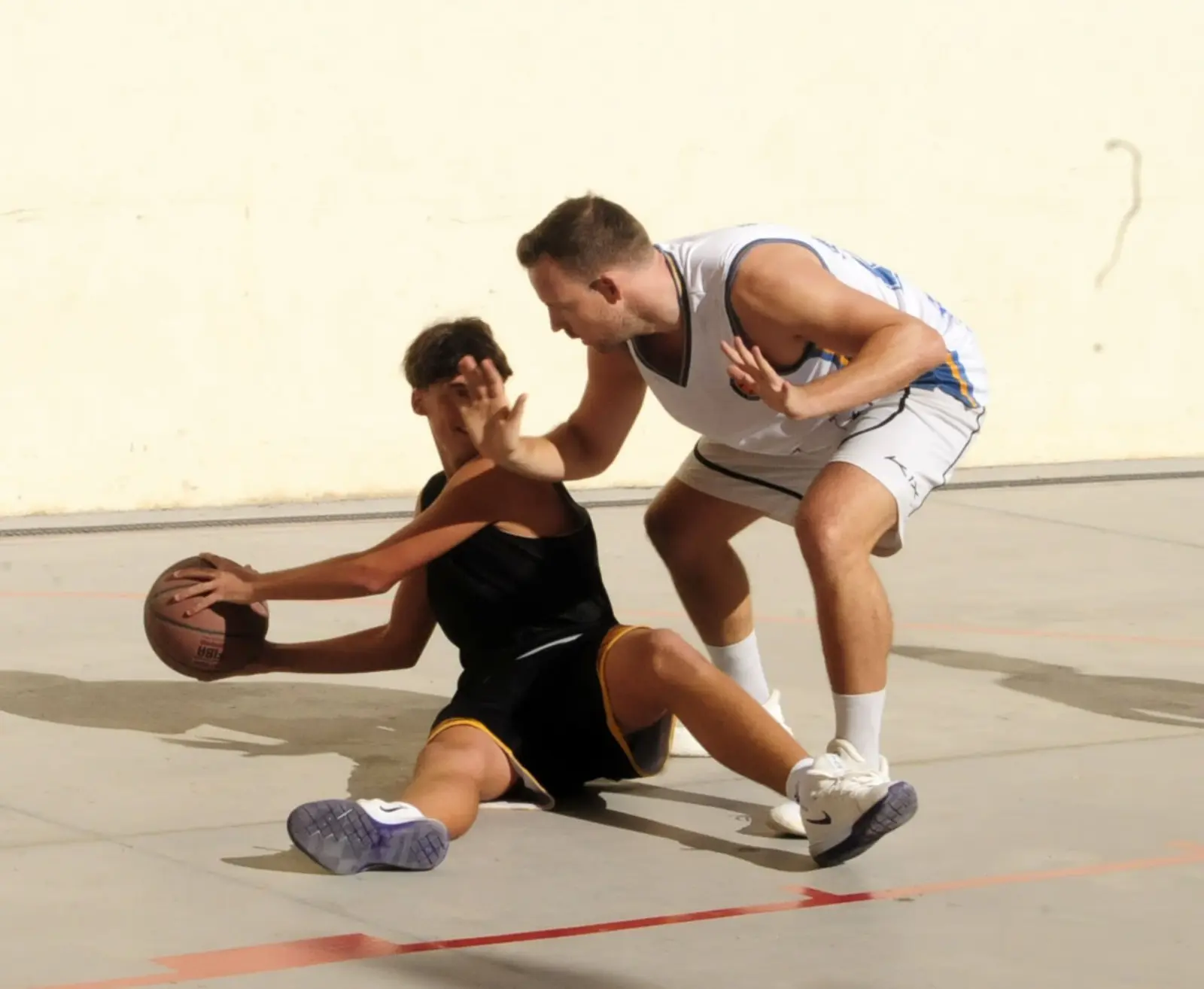 Jugadora defensant mentre regateja asseguda a terra